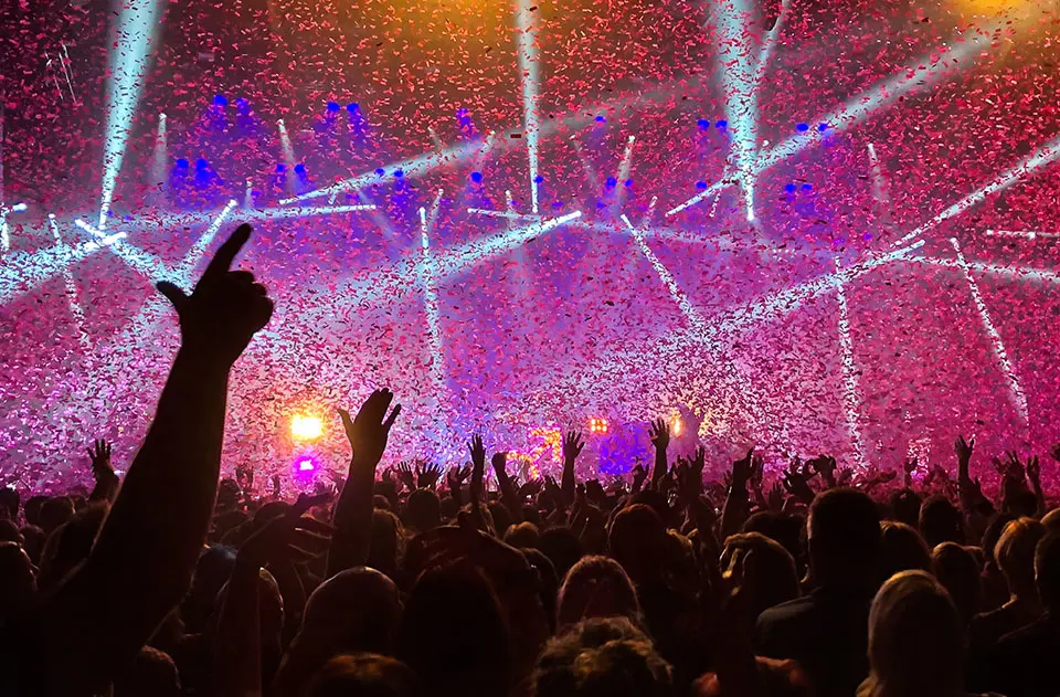 A crowd of people in front of a stage with lights.